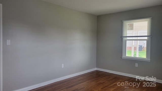 spare room featuring baseboards and dark wood-type flooring