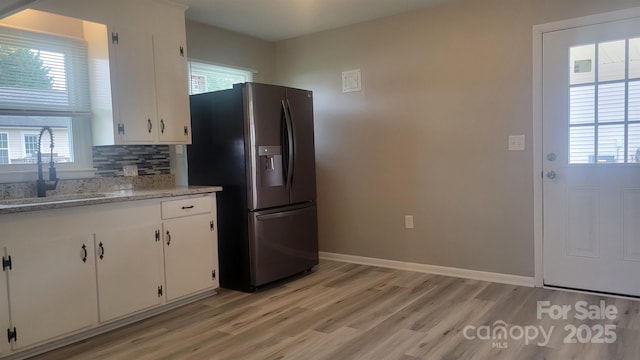 kitchen featuring white cabinetry, light wood-style flooring, stainless steel fridge, and a sink