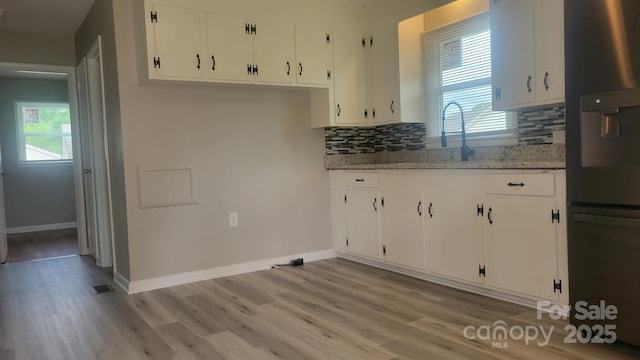 kitchen with white cabinets, fridge with ice dispenser, and light wood-style floors