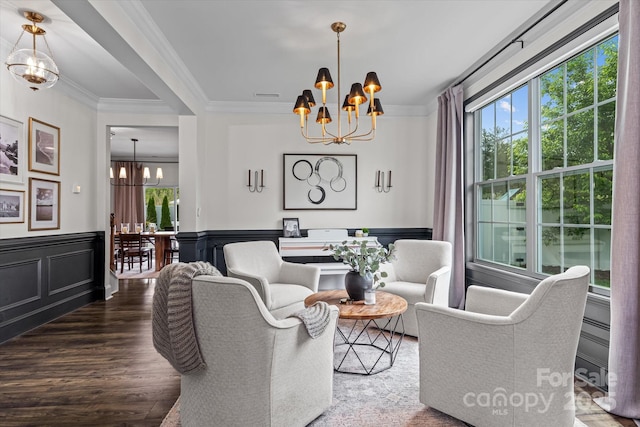living area featuring a chandelier, wainscoting, ornamental molding, and wood finished floors
