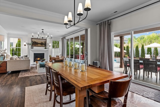 dining space featuring visible vents, a lit fireplace, an inviting chandelier, ornamental molding, and dark wood finished floors