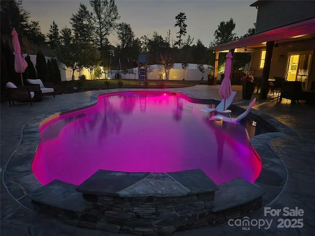 pool at dusk with ceiling fan, a fenced backyard, a fenced in pool, and a patio area