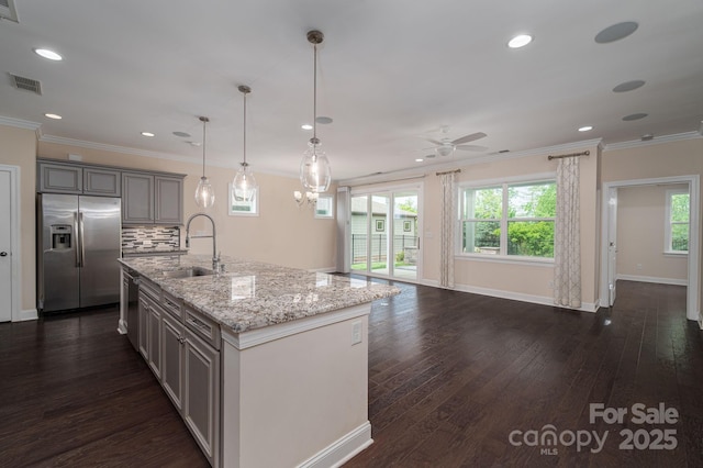 kitchen featuring a sink, ceiling fan, appliances with stainless steel finishes, light stone countertops, and visible vents