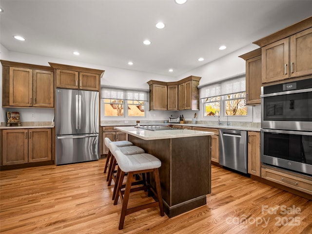 kitchen featuring recessed lighting, a sink, stainless steel appliances, a kitchen breakfast bar, and a center island