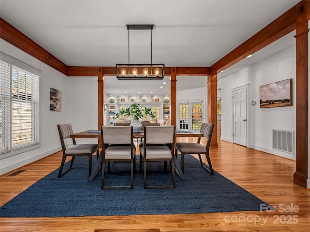 dining room with visible vents, wood finished floors, a wealth of natural light, and a notable chandelier