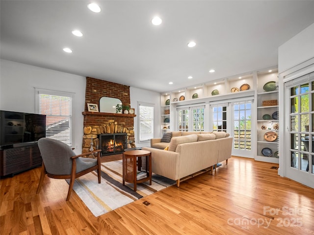 living room featuring recessed lighting, light wood-style floors, a fireplace, and built in features