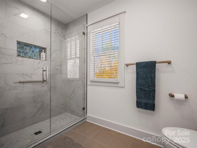 full bathroom with toilet, a shower stall, and baseboards