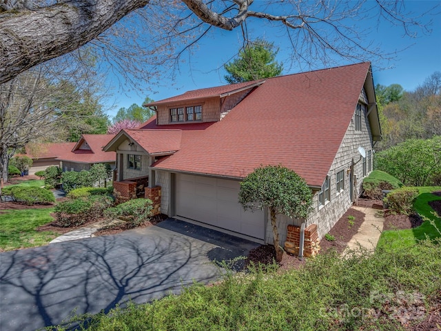 view of front of house with driveway, a shingled roof, and an attached garage