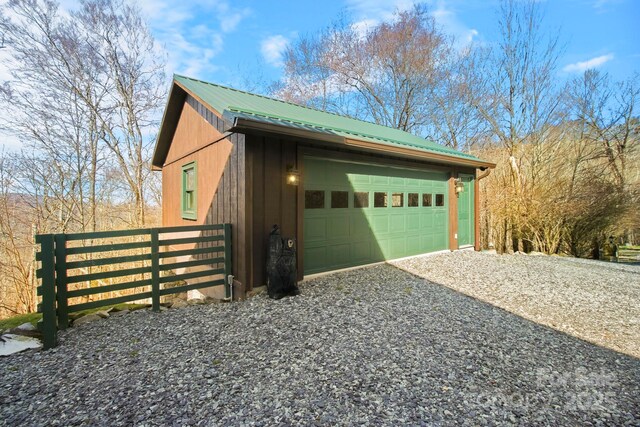 view of property exterior with fence, a detached garage, and metal roof