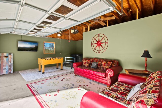 living room featuring concrete floors, a ceiling fan, and a garage