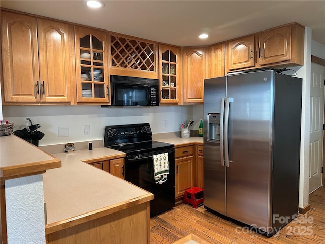 222 Creekside Way, Burnsville, NC 28714 - kitchen with black appliances, light wood-style flooring, light countertops, recessed lighting, and glass insert cabinets