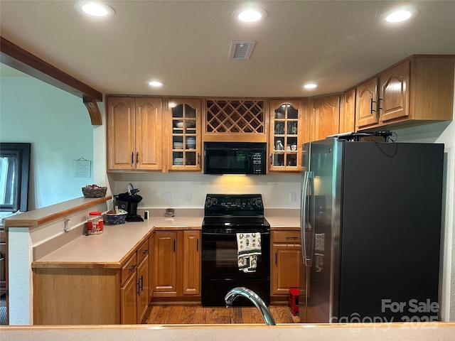 222 Creekside Way, Burnsville, NC 28714 - kitchen with black appliances, a peninsula, recessed lighting, glass insert cabinets, and light countertops