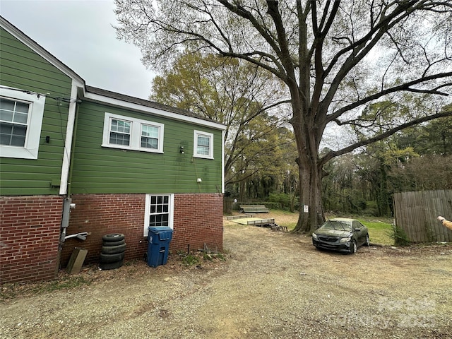 view of side of home featuring brick siding and fence