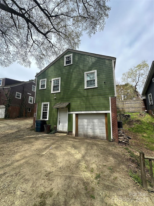 back of property with an attached garage, fence, and driveway