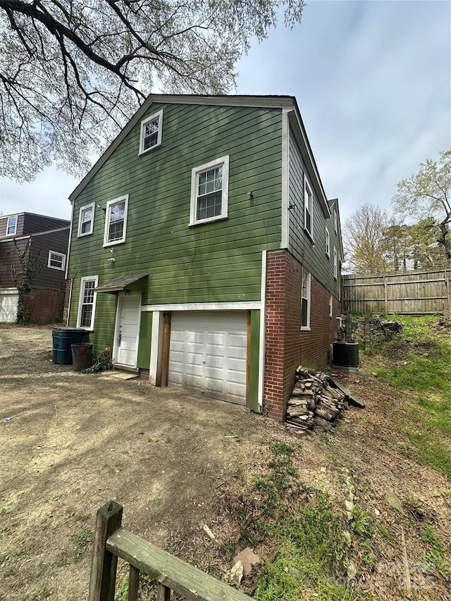 rear view of house with an attached garage, fence, and driveway