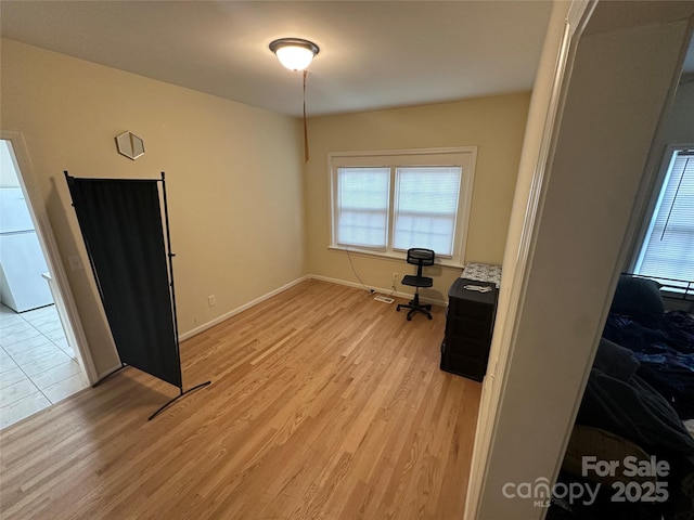 unfurnished office with baseboards, a healthy amount of sunlight, and light wood-type flooring
