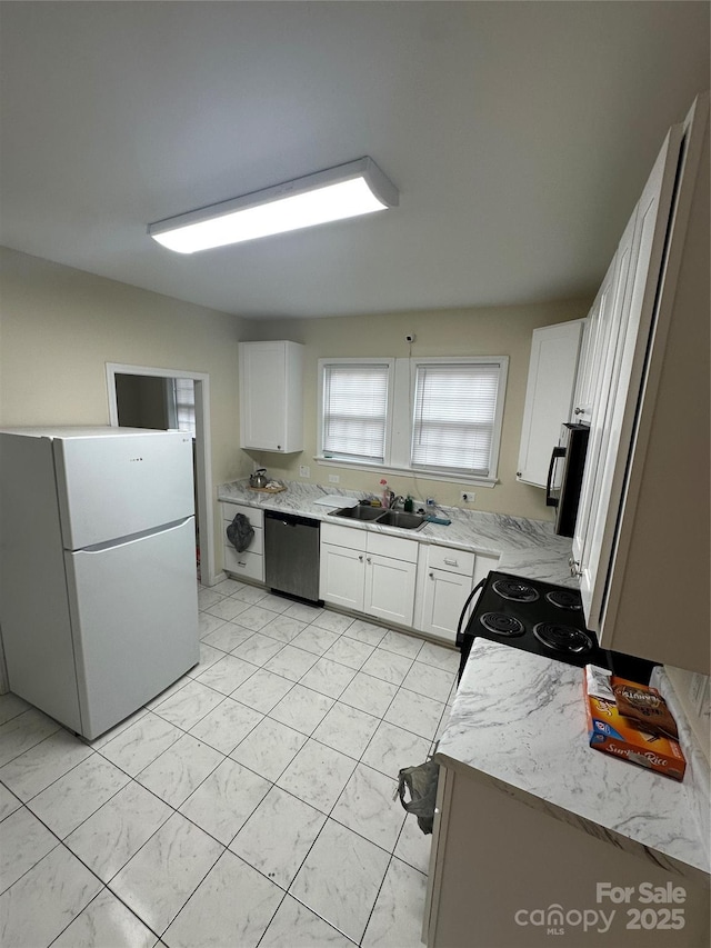 kitchen featuring freestanding refrigerator, white cabinets, a sink, and dishwasher