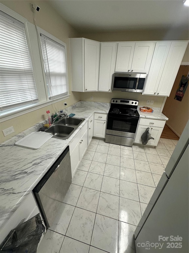 kitchen featuring a sink, appliances with stainless steel finishes, white cabinetry, and marble finish floor