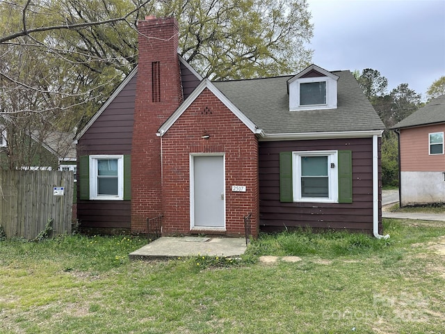 view of front facade featuring fence, a chimney, a shingled roof, and a front yard