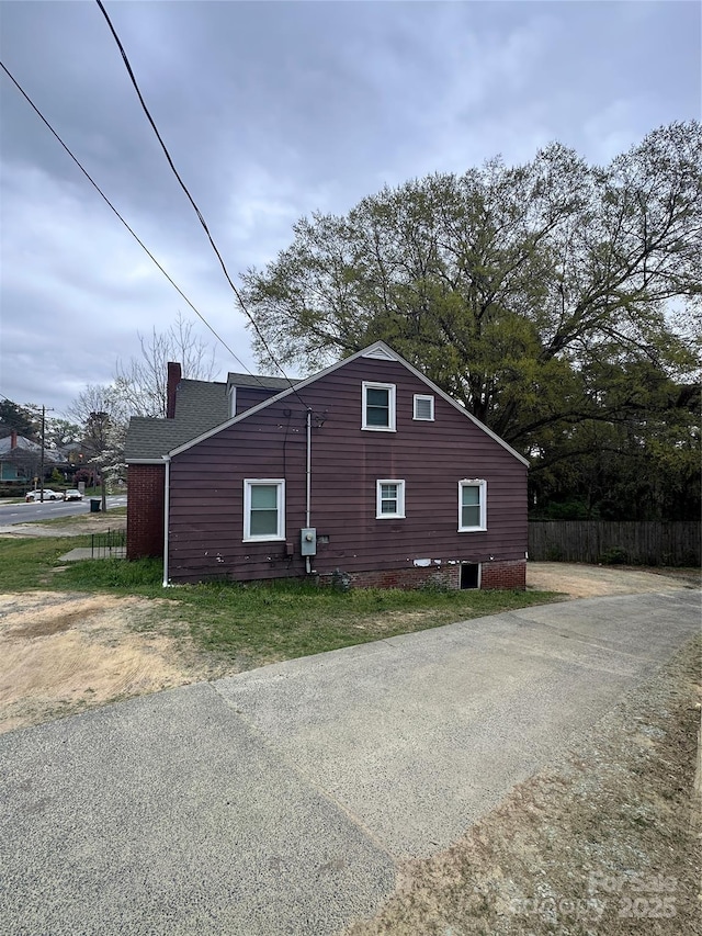 view of side of home with fence and a chimney