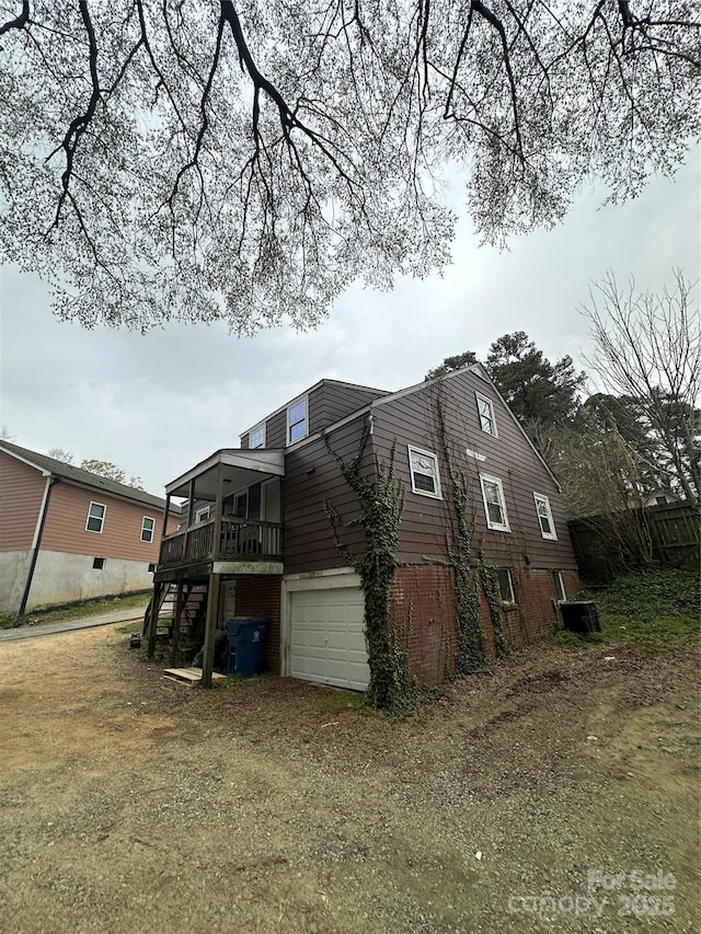 view of side of home featuring stairs, an attached garage, driveway, and a deck