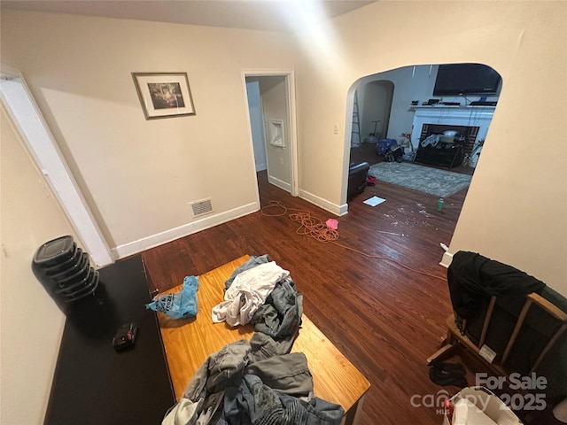 interior space with visible vents, arched walkways, baseboards, and wood finished floors