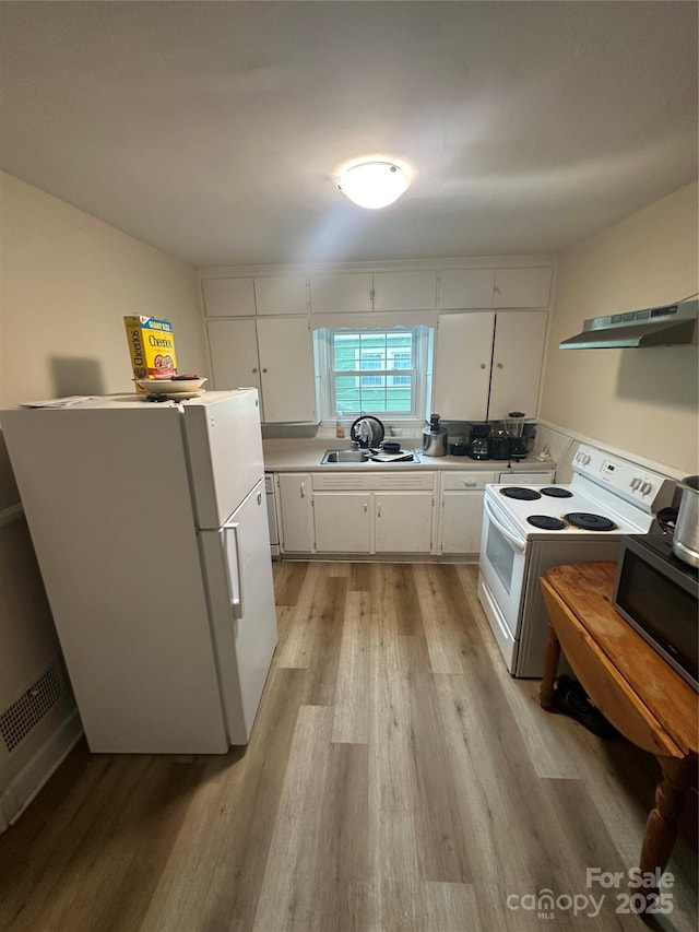 kitchen featuring white appliances, white cabinets, under cabinet range hood, and light wood finished floors