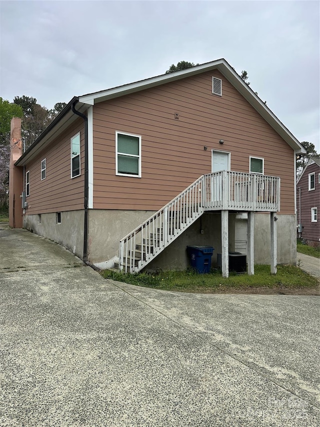 rear view of property with stairs and concrete driveway