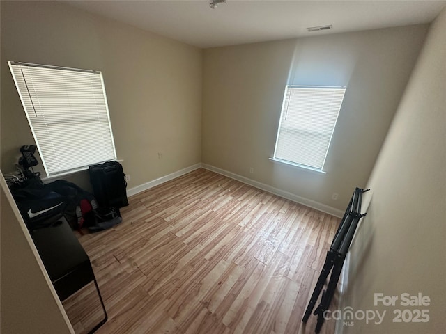 unfurnished room with baseboards, light wood-type flooring, and visible vents