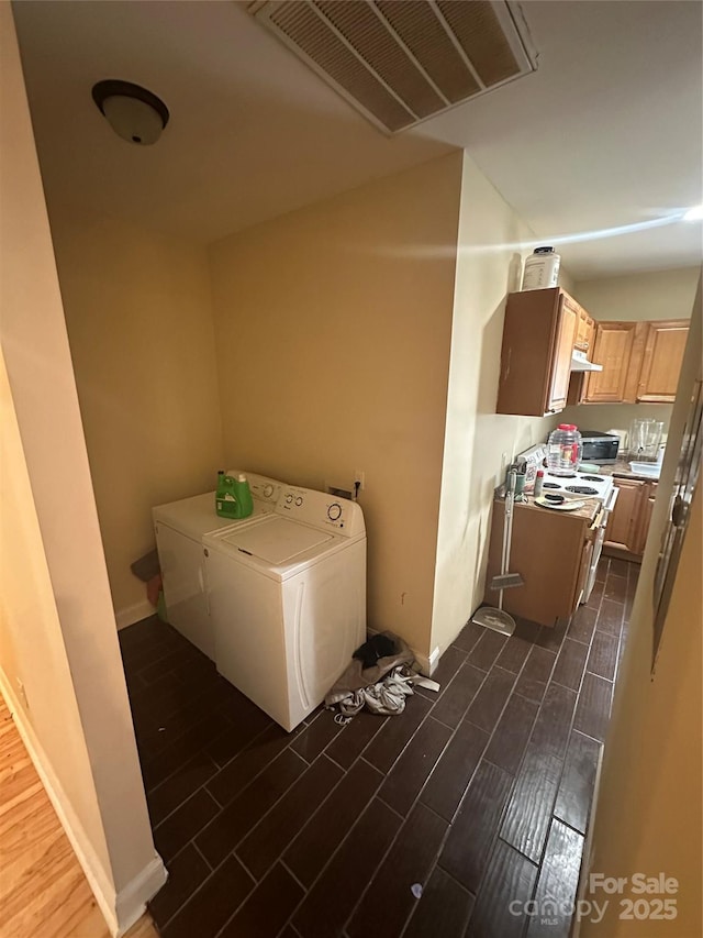 clothes washing area with washer and dryer, laundry area, visible vents, and wood tiled floor