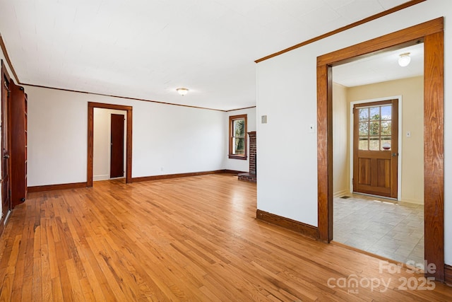 spare room with baseboards, crown molding, and light wood-type flooring