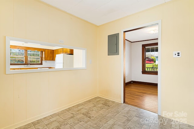 empty room featuring a sink, electric panel, stone finish flooring, baseboards, and ornamental molding