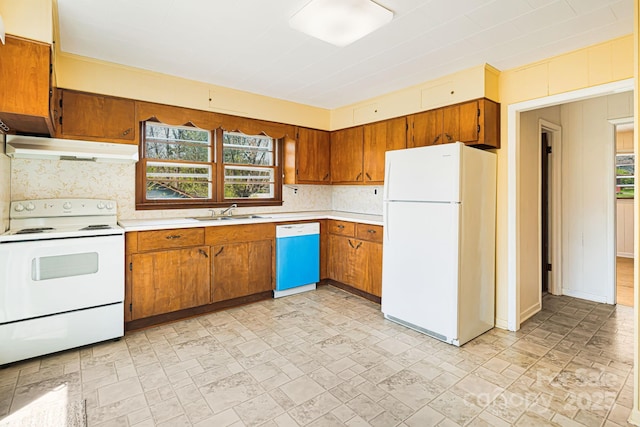 kitchen featuring under cabinet range hood, light countertops, white appliances, and a sink