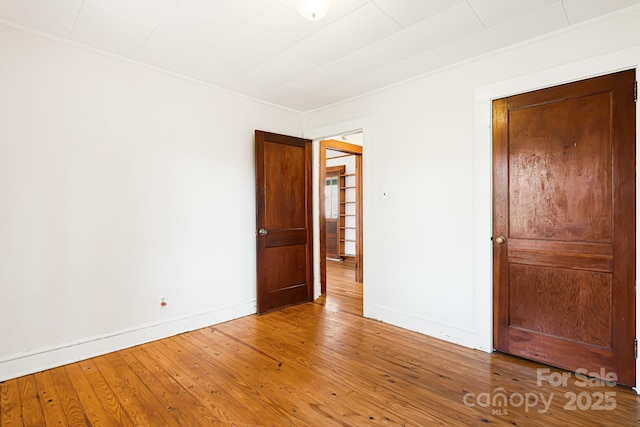 unfurnished bedroom with hardwood / wood-style flooring, baseboards, and ornamental molding