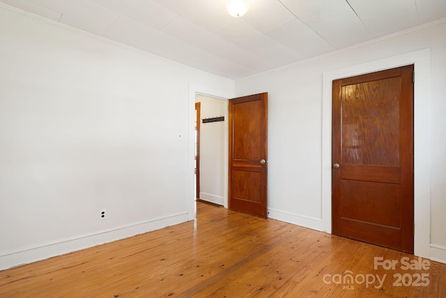 unfurnished bedroom featuring baseboards, wood finished floors, and crown molding