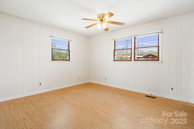 unfurnished room featuring ceiling fan, baseboards, visible vents, and light wood-type flooring