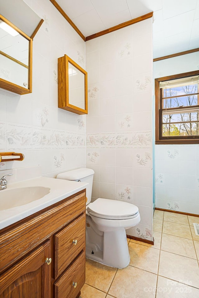 bathroom with tile patterned flooring, toilet, vanity, ornamental molding, and tile walls