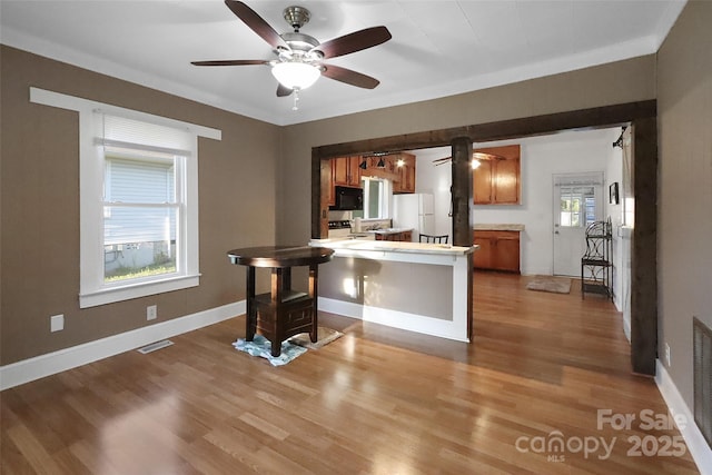 kitchen with brown cabinets, visible vents, a ceiling fan, freestanding refrigerator, and black microwave