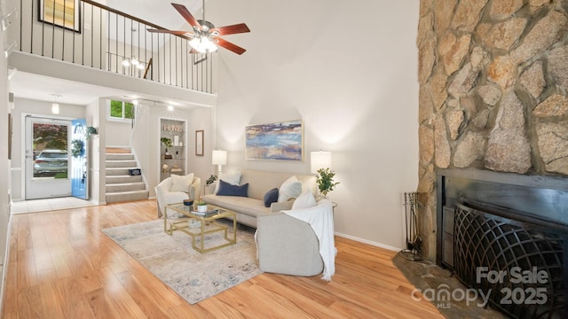 living area with stairway, wood finished floors, a ceiling fan, and a high ceiling