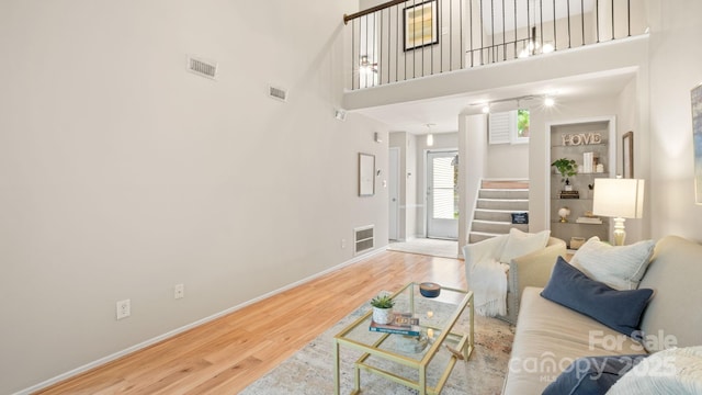 living area featuring stairway, wood finished floors, visible vents, and baseboards