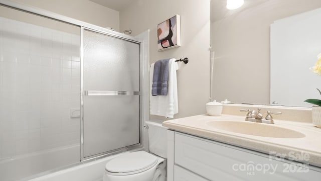 full bathroom with combined bath / shower with glass door, vanity, and toilet