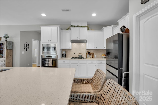 2655 Stonewood Vw, Kannapolis, NC 28081 - kitchen with appliances with stainless steel finishes, backsplash, white cabinetry, recessed lighting, and light stone countertops