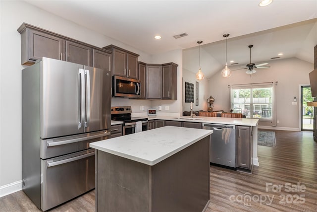 kitchen featuring visible vents, a sink, dark wood-type flooring, a peninsula, and appliances with stainless steel finishes
