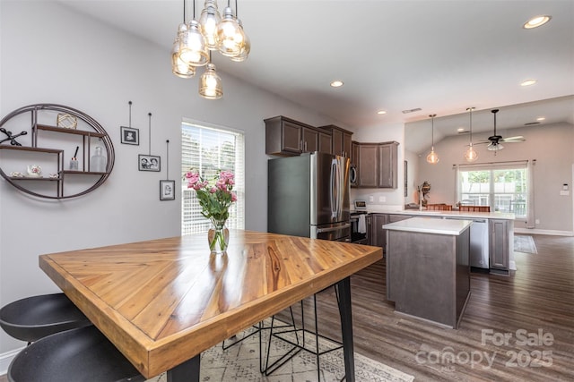 kitchen featuring stainless steel appliances, a peninsula, dark wood finished floors, dark brown cabinetry, and light countertops
