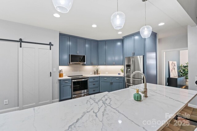 kitchen with tasteful backsplash, a sink, decorative light fixtures, blue cabinetry, and appliances with stainless steel finishes