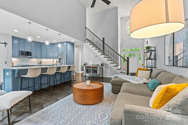 living area with recessed lighting, dark wood finished floors, stairway, a towering ceiling, and a ceiling fan