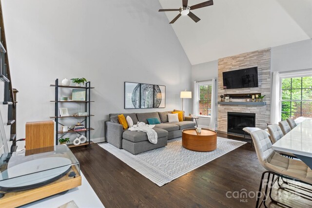 living room with baseboards, wood finished floors, a large fireplace, ceiling fan, and high vaulted ceiling