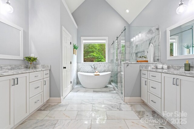 bathroom featuring two vanities, a shower stall, a freestanding tub, and lofted ceiling