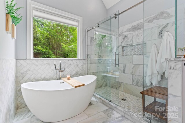 full bath featuring tile walls, marble finish floor, a freestanding bath, and a stall shower