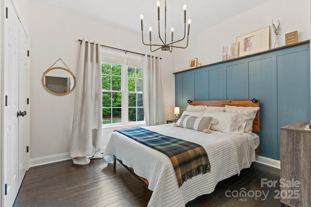 bedroom featuring baseboards, dark wood-style flooring, and an inviting chandelier